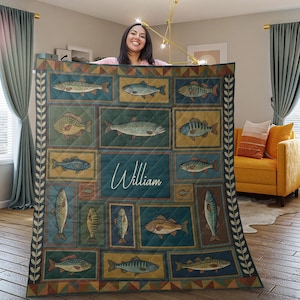 Puede incluir: Una colcha acolchada con un patrón repetido de ilustraciones de peces en marcos rectangulares. La paleta de colores incluye verde azulado, dorado y marrón. El nombre "William" se muestra en cursiva en la colcha.