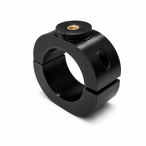 May include: A black circular mounting clamp featuring a split design for adjustable tension. The component includes a top-mounted circular knob with a central brass-colored threaded metal insert and a side-facing circular opening for attachment.