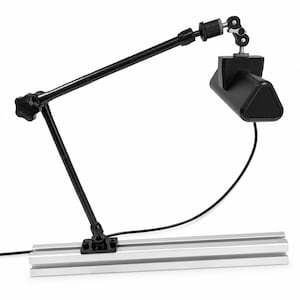 May include: A black adjustable articulated arm lamp mounted on a silver aluminium T-slot extrusion rail. The lamp features a triangular head, a central locking knob, and a thin black power cord extending from the base of the light fixture.