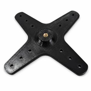 May include: A black, X-shaped mounting bracket with a textured surface. The component features four arms, each with three circular holes, and a central raised circular hub containing a threaded brass insert for secure attachment and hardware mounting.