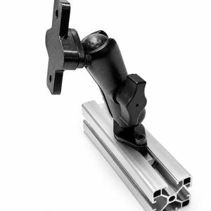 May include: A black adjustable ball-and-socket mounting arm attached to a silver aluminum T-slot extrusion profile. The mount features a flat rectangular plate with two circular holes at the top and a tightening knob on the side for positioning.