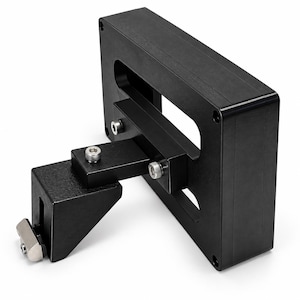 May include: A black anodized aluminum mounting bracket featuring a rectangular frame with a central cutout, attached to an adjustable L-shaped support arm. The assembly includes three silver-colored hex bolts and a T-shaped metal fastener at the end.