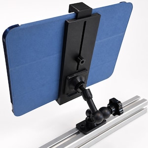 May include: A black adjustable tablet mount attached to a silver aluminum extrusion rail. The mount features a central black plastic bracket holding a blue tablet case, connected by a multi-jointed black arm with a tightening knob for positioning.