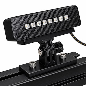 May include: A black LED light bar with a carbon fiber pattern finish, featuring seven individual circular light bulbs. The unit is mounted on a black metal bracket with two silver screws and an adjustable hinge mechanism attached to a rail.