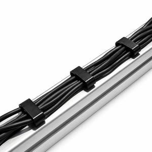 May include: A silver-coloured metal cable management channel featuring a series of black plastic clips that secure multiple black electrical cords in a parallel arrangement along the length of the track, creating an organised cable routing system.