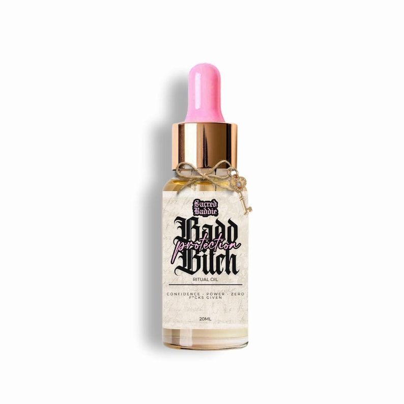 Puede incluir: Una botella de vidrio de aceite ritual con un cuentagotas rosa y tapa dorada. La etiqueta dice "Sacred Baddie, protection Bitch, Ritual Oil". Un peque&ntilde;o dije de llave cuelga de la botella. La botella contiene 20 ml de aceite.