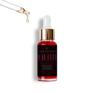 May include: A clear glass dropper bottle filled with vibrant red oil, featuring a black label with the text LILITH DARK FEMININE RITUAL OIL. A separate glass dropper tip is positioned above the bottle with a single drop of golden oil suspended.