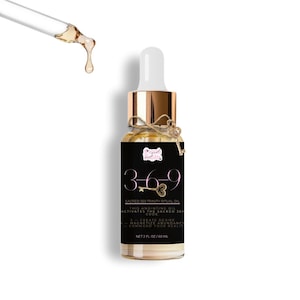 May include: A clear glass bottle of Sacred 369 Trinity Ritual Oil with a gold cap and a dropper. The label is black with white text and the numbers 3-6-9. The bottle is adorned with a small key charm and a bow. The bottle contains 2 fl oz / 60 ml of oil.