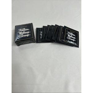 May include: A collection of black Avon Fashion Makeup Group samples. The box and individual packets feature white text and gold accents. The samples are for Super Moisturizing Creamy Luminous Foundation.
