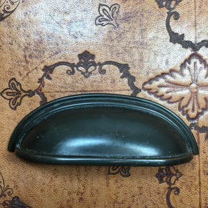 May include: A dark green cabinet pull with a rounded, arched shape. The pull has a smooth, slightly shiny finish.