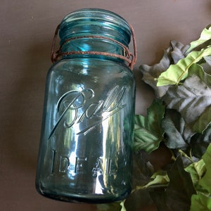 Peut inclure: Un bocal en verre bleu vintage Ball Ideal avec un couvercle en métal rouillé et une anse en fil de fer.