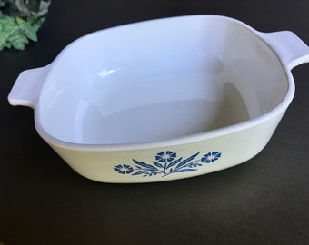 Puede incluir: Plato para hornear de cerámica blanca con diseño floral azul. El plato tiene dos asas a los lados.