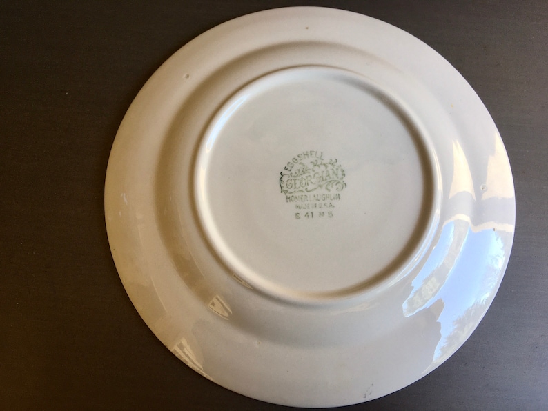 May include: White ceramic plate with a green "Eggshell Gearhart" logo on the bottom. The logo includes the words "Homer Laughlin China Co.  U.S.A." and "E 41 H 5".