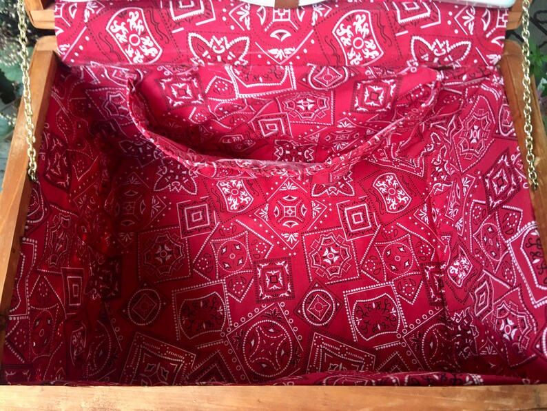 May include: A wooden box with a red and white bandana lining. The box has a hinged lid and a metal chain.