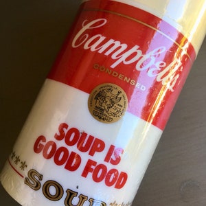 May include: A white and red Campbell's Soup can with the text "Soup is Good Food" and a gold seal with the text "Exposition Universelle Internationale 1900".