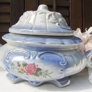 May include: A blue and white porcelain trinket box with a floral design and a lid. The box has a scalloped edge and a gold trim.