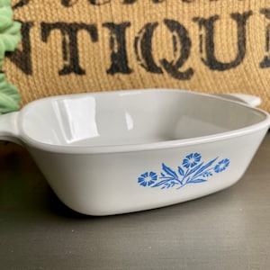 Puede incluir: Plato para hornear de cerámica blanca con diseño floral azul. El plato tiene dos asas a los lados.