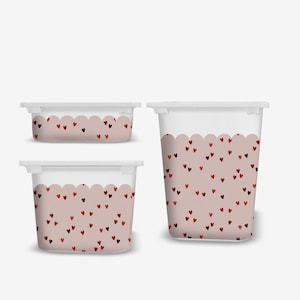 May include: Three clear plastic storage containers with white lids. The containers have a scalloped design with a pink background and scattered red hearts. The containers are different sizes, suitable for various storage needs.