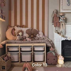 May include: A child's room with a wooden storage unit filled with pink and gray bins. The room features a striped wall, plush toys, and decorative items, including a mushroom lamp and a strawberry-shaped basket. The text "Color 13" is visible.