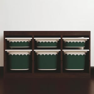 May include: A dark brown wooden storage unit with six compartments, each holding a green and white scalloped-edge bin. The bins are arranged in two rows of three, offering a stylish storage solution for any room.