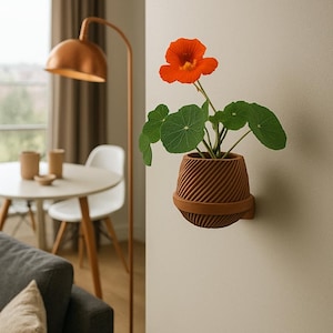 May include: A brown, textured wall-mounted planter holding a plant with an orange flower and green leaves. The planter, made of a ridged material, is fixed to the wall with a matching bracket. The plant provides a bright contrast in a neutral-toned room.