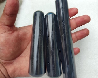 May include: Three dark blue, cylindrical objects with rounded ends are held in a hand. The objects vary in length, with a smooth, glossy finish. The items appear to be made of a solid, possibly polished material.