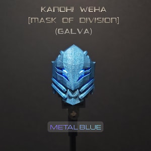 以下が含まれることがあります： 「KANOHI WEHA [MASK OF DIVISION] (GALVA)」と「METAL BLUE」の文字が入ったメタリックブルーのマスク。マスクはテクスチャ加工された表面と、光る青色のアクセントを持つ幾何学的なデザインです。