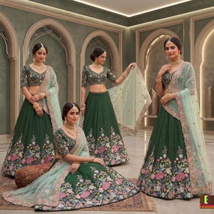 May include: Four women wearing matching green embroidered lehengas with floral patterns. Each outfit includes a matching top and a sheer, light green dupatta. Gold jewelry and headpieces complete the look. The setting is an ornate room with arched doorways.
