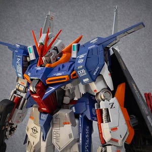 May include: A detailed model of a robot with a blue, white, orange, and red color scheme. The robot has intricate mechanical details, including panels, joints, and weapons. The model is posed against a gray background.