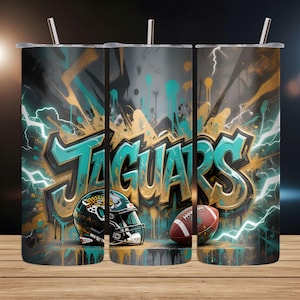 May include: A set of three stainless steel tumblers with lids and straws. Each tumbler features a graffiti-style design with the word "JAGUARS" in teal and gold, along with a football helmet and football. Teal and white lightning bolts and paint drips complete the design.