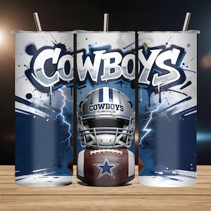 May include: A set of three stainless steel tumblers with lids and straws. Each tumbler features a design with the word "Cowboys" in white and blue graffiti style, a football helmet, and a football with a star logo. The background has a blue and white lightning design.