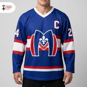 May include: A blue hockey jersey featuring a white V-neck collar, long sleeves with white and red horizontal stripes, and the number 24 on the sleeves. The chest displays a large M logo with a fleur-de-lis and the letter C on the upper left.