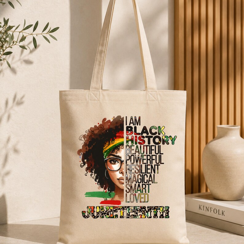 May include: Beige tote bag featuring a graphic of a Black woman with glasses and a colorful head wrap. Text includes "I AM BLACK HISTORY BEAUTIFUL POWERFUL RESILIENT MAGICAL SMART LOVED" and "JUNETEENTH".