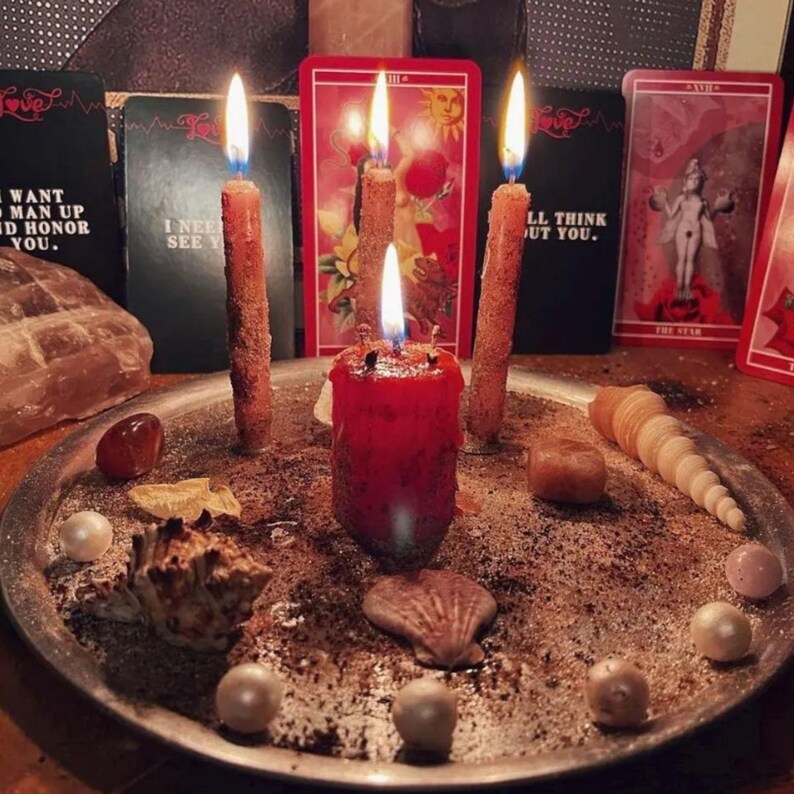 A tarot card reading setup with candles, seashells, and other objects arranged on a tray.