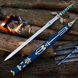 Puede incluir: Una espada plateada con una empu&ntilde;adura detallada y una vaina azul y dorada. La espada tiene una hoja larga y puntiaguda y una empu&ntilde;adura con detalles dorados y un agarre turquesa. La vaina es azul oscuro con dise&ntilde;os dorados.