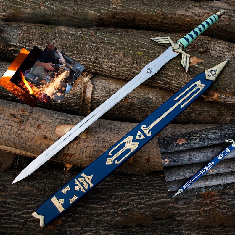 Puede incluir: Una espada plateada con una empu&ntilde;adura detallada y una vaina azul y dorada. La espada tiene una hoja larga y puntiaguda y una empu&ntilde;adura con detalles dorados y un agarre turquesa. La vaina es azul oscuro con dise&ntilde;os dorados.