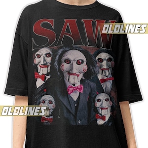Könnte beinhalten: Schwarzes T-Shirt mit einer Grafik der Saw-Filmfigur Billy the Puppet und dem Wort "SAW" in Rot. Das Bild zeigt mehrere Billy the Puppet-Figuren in Anzügen und Fliegen, ein Horrorfilm-Thema.