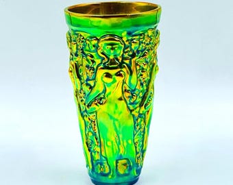 Peut inclure: Un vase en verre vert irisé avec un bord doré. Le vase présente un motif en relief d'une femme et de personnages. Le vase mesure environ 18 cm de haut.