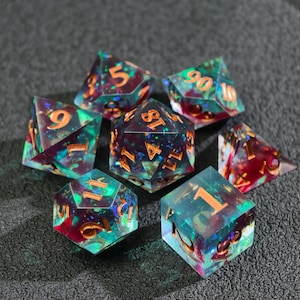 Peut inclure: Ensemble de sept dés polyédriques aux teintes irisées de turquoise, violet et rouge. Les dés ont des chiffres dorés et sont conçus pour les jeux de rôle sur table. Les dés sont en résine transparente.