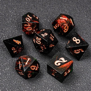 May include: Set of seven polyhedral dice with a black base and copper-colored numbers. The dice have a red and green internal design. The dice are for tabletop role-playing games.