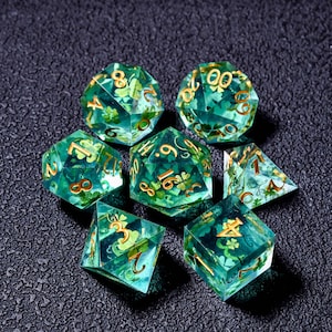 Könnte beinhalten: Ein Set aus sieben polyedrischen Würfeln in transparentem Grün. Jeder Würfel hat goldfarbene Zahlen und ist mit grünen Kleeblattmustern gefüllt. Geeignet für Tischrollenspiele.
