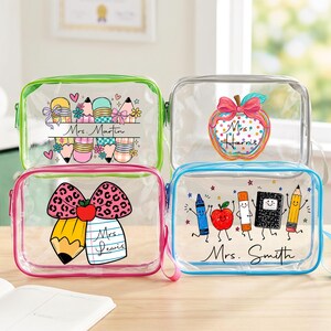 May include: Four rectangular clear vinyl pouches with coloured zips. The top left features pencils and the text Mrs. Martin. The top right shows an apple with a bow and Mrs. Harris. The bottom left has a bow, pencil, and Mrs. Lewis. The bottom right shows school supplies and Mrs. Smith.