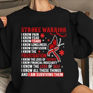 May include: Black sweatshirt with the text "STROKE WARRIOR" in red. The design includes a red ribbon, a butterfly, and the phrases "I KNOW PAIN", "I KNOW FEAR", "I KNOW TEARS", and "I AM SURVIVING THEM".