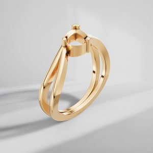 Pode incluir: Uma cravação de anel de ouro com um design aberto único. O anel apresenta uma montagem central para uma pedra preciosa e uma haste de banda dupla. O ouro polido reflete a luz, destacando as curvas elegantes e a estética moderna do anel.