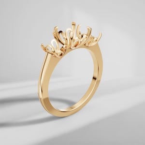 May include: A polished yellow gold ring setting featuring a multi-prong head designed to hold multiple stones. The band is smooth and solid, leading up to an intricate, open-work gallery structure with several curved prongs extending upward.