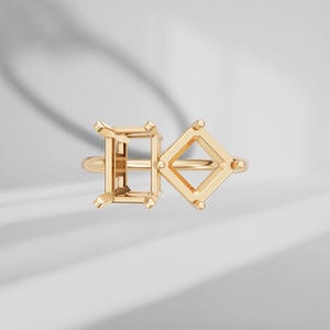 Puede incluir: Un engaste de anillo en oro con dos cabezales de montaje distintos. Uno es de forma rectangular para una piedra de corte esmeralda, mientras que el otro es cuadrado para una piedra de corte princesa. Ambos están unidos a un aro liso.