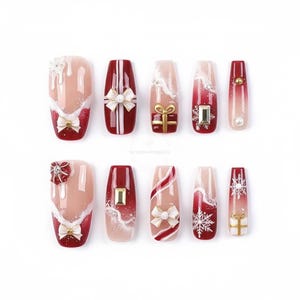 May include: A set of ten artificial nails with a festive Christmas theme. The nails feature designs including bows, gift boxes, snowflakes, and pearl accents. Colors include red, white, gold, and nude.
