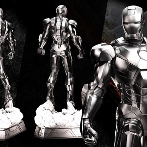 May include: A silver Iron Man statue in three views. The statue is on a white cloud-like base. The words "AVENGERS ASSEMBLE" are in the upper left corner. The statue is highly detailed with a metallic finish.