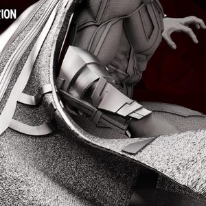 May include: A grayscale diorama figure with the text "WandaVision Diorama" in the upper left corner. The figure has a metallic silver and grey colour scheme, with intricate details on the armour and cape. The figure's arm is outstretched, and the background is a dark red.