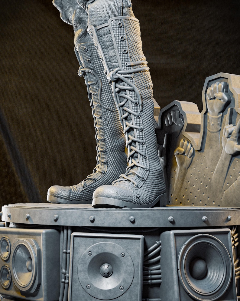 May include: Gray, textured knee-high boots with lace-up closures. The boots are on a platform with speaker components and a sculpture of raised fists. The boots have a detailed, quilted pattern and are made of a durable material.